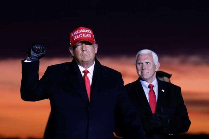 Mike Pence (right) looking at Donald Trump (left) wearing a Make America Great Again hat.